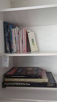 Books arranged upright on shelf, showing a variety of titles and sizes.