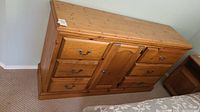 Front view of solid pine wood dresser featuring six drawers and a central cabinet door with metal handles.