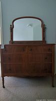 Front view of wooden dresser with attached mirror showing overall condition and design.