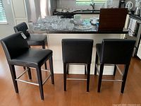Front and side view of four chairs placed at kitchen island counter