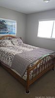 Queen size bed set assembled in a bedroom, showing wood bed frame with floral bedding and quilt
