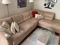 Main view showing full left and right sections of the beige sectional with pillows and coffee table in front