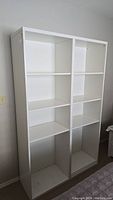 Full front view of the white shelving unit showing both vertical sections with adjustable shelves.