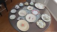 Wide view of the assorted teacups, saucers, plates, and dishes arranged on glass table