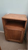 Front and side view of teak wood nightstand showing open shelf and cabinet door with handle.