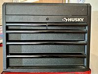 Front view of closed black Husky tool chest with lockable lid and drawers
