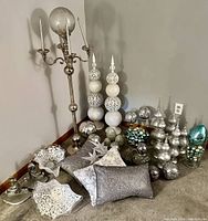 Wide view of all decor items including candelabra, finial-style pillars, glitter globes, and throw pillows arranged on the floor