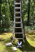 Aluminum ladder set up in A-frame configuration with platform and hinge assembly at base