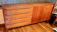 Full front view of teak sideboard showing four drawers and two sliding doors.