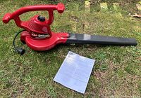 Photo of the full Toro Ultra Blower Vac device on grass with the manual placed beside it, showing the entire unit including the nozzle and handles.