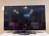 Front view of the 40 inch Samsung TV on its stand with remote control placed in front.