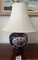 Full view of the lamp with white fabric shade on wooden base showing overall proportions and colors.