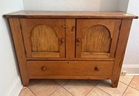 Front view of pine console cabinet showing two arched doors and bottom drawer with knob handles