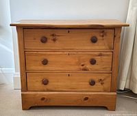Front view of the antique pine dresser showing three drawers with wooden knobs and natural finish.