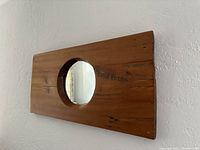 Front view of rectangular pine wood mirror frame with round cutout inset mirror at center, showing natural wood grain and patina.