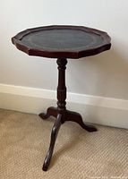 Side view of the mahogany pie crust lamp table showing the turned central column and tripod feet, carpet background.