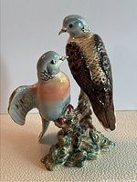 Front angled view showing both birds, their colorful glazes, and the leafy base with glaze crazing visible.