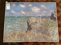 Overall view of the framed print showing the landscape scene of the cliff and sea with two figures and clouds in the sky.