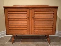 Front view showing two louvered doors and tapered legs