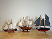 Front view of three model sailboats on stands showing size, colors and details.