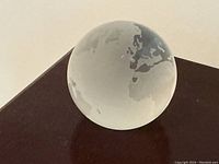 Photo of the crystal globe paperweight showing the continent of Europe, clearly etched as frosted areas on the transparent glass sphere.