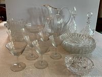 Full lot view showing all items: crystal decanters, water pitcher with gold trim, multiple glasses, and bowls arranged on white cloth.
