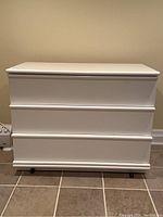 Front view of the white three-drawer chest showing clean lines and drawer fronts.