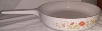 Side view of vintage Corning Ware range topper skillet with wildflower pattern and long handle