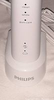 Close-up of the toothbrush charging base showing Philips branding and indicator lights for clean, white, gum care modes.