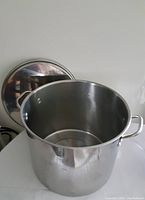 Empty 20L stainless steel stock pot with lid placed behind