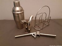 Set of kitchen and bar items including cocktail shaker, salt and pepper shakers, and napkin holder arranged on a surface.