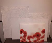 Six canvas wall artworks, five white textured canvases stacked behind and one red poppy flower canvas in front.