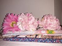 Three large realistic faux flower heads placed on top of three folded fabrics showing floral and patterned designs