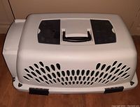 Top view of beige kennel pet carrier with black handle and ventilation holes.