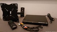 Sony black HDMI CD DVD Player with remote and RCA cables on table.