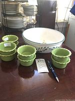 Large white ceramic bowl with green leaf pattern and 8 green ramekins arranged in front