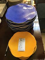 Stack of blue plates with scalloped edges and textured surface along with stack of gold plates.