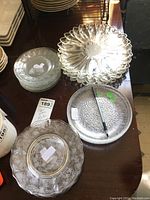 Overview of the glass plates including shadow of person taking the photo, with clear plates showing floral etching, bubble texture, and other patterns.