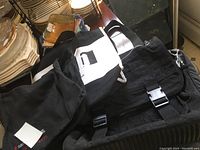 Four black laptop bags piled together, showing different styles including a black and white color block flap with adjustable buckle.