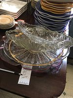 Four stacked glass bowls with etched floral patterns and gold highlights on handles and rims. Bowls vary in size with the largest being long and large, and a smaller oval bowl on top.