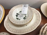 Platter and some bowls stacked inside it showing white rose design on ceramic with gold filigree border.