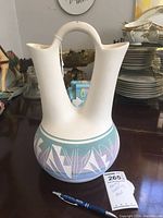 Front view of the Navajo wedding vase showing the double spout, handle, and geometric design on the base with visible dirt.