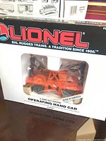 Front view of original boxed Lionel O gauge operating hand car, showing model through plastic window and brand logo on top