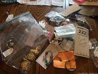 Assorted costume pierced earrings in plastic bags, including gold-tone hoops and bead dangles on wooden surface.