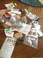 Mixed lot of pierced costume earrings in various styles, placed on a wooden surface, some in plastic bags and on cards.