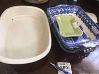 Full lot of four rectangular dishes including the large white ceramic dish, blue and white patterned glass dish, small green ceramic dish, and clear textured glass dish.