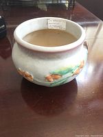 Side view of the Roseville Bittersweet ceramic planter showing embossed bittersweet design with orange berries and green leaves on cream background.