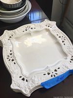 First photo of one square white ceramic plate with grapevine embossed decoration and cutout rim.