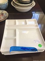 Four white ceramic sushi plates stacked, showing the segmented design and measuring roughly 9 x 9 inches per plate.