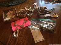Overview photo showing six wristwatches with varying bands and several jewelry sets including a rhinestone necklace and bracelet set, earrings and pin set, and a zipped plastic bag with additional jewelry.